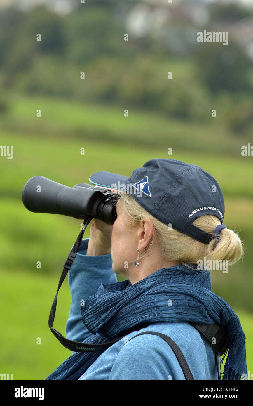 Eine Frau oder Lady vogelbeobachtung an der RSPB Nature Reserve an Brading Marsh auf der Isle of Wight mit Fernglas und lesen Ratgeber. birding zucken Stockfoto