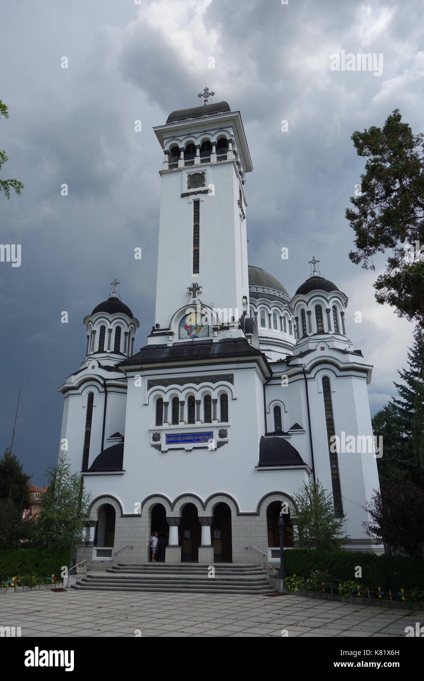 Dreifaltigkeitskirche mit rumänischer Flagge und wolkenverirlter Himmel. Sighisoara, Siebenbürgen, Rumänien Stockfoto