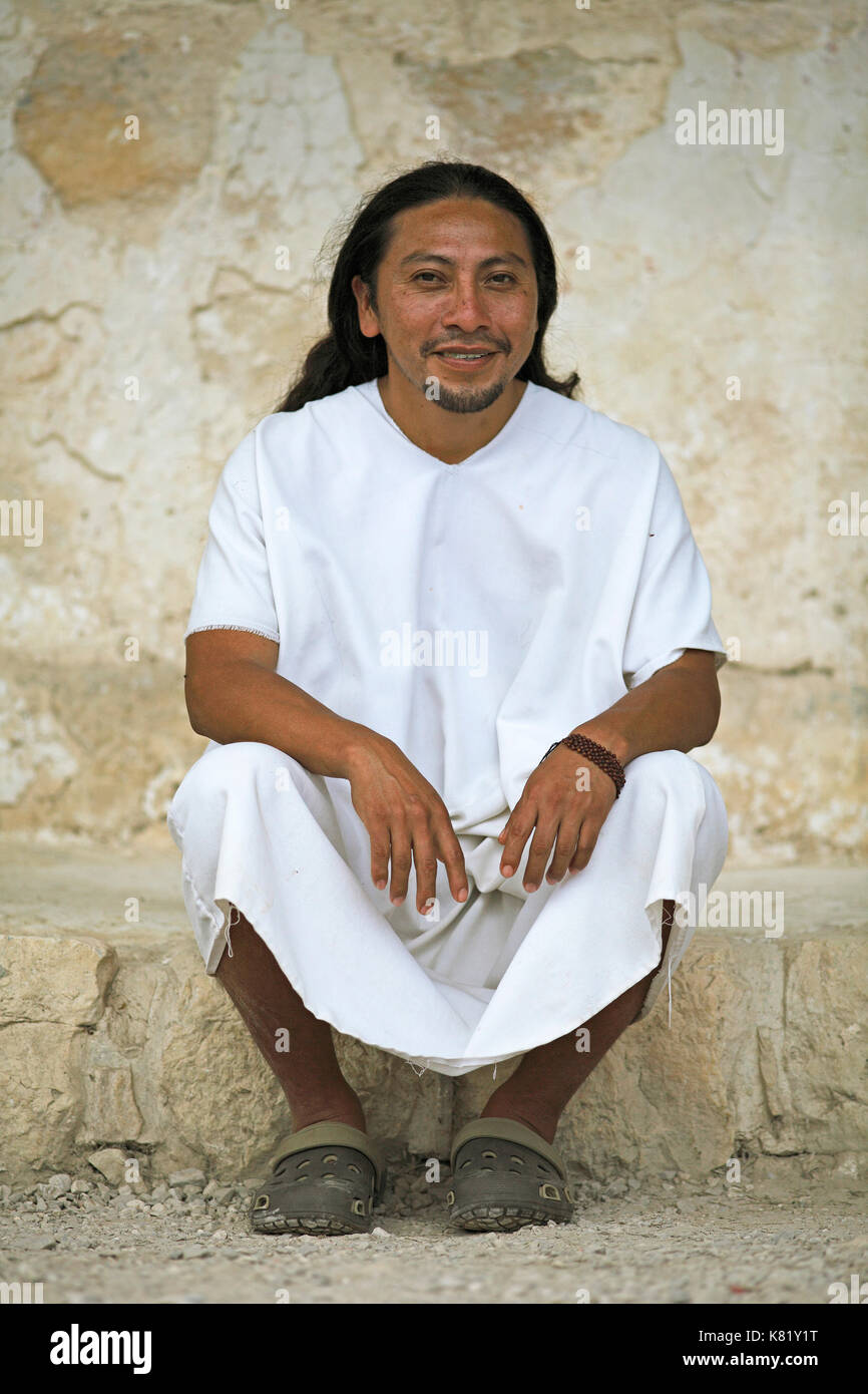 Mann, 36 Jahre alt, Lacandone ethnische Gruppe, an der Wand sitzen, in traditionellen weißen Kleid für Männer, Maya Selva Lacandona Stockfoto