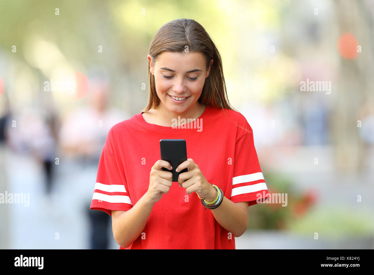 Vorderansicht eines glücklichen jugendlich mit einem smart phone gehen auf die Straße Stockfoto