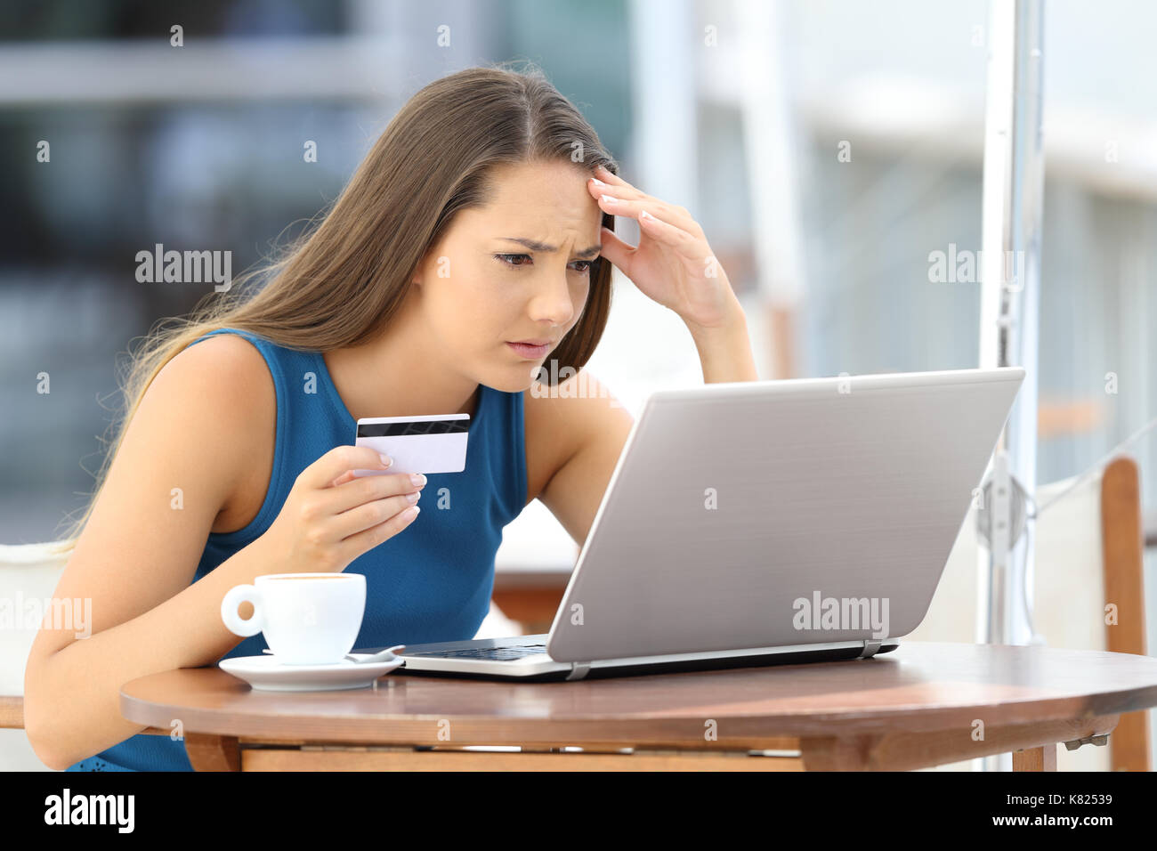 Besorgt auf Linie Käufer versuchen, mit einer Kreditkarte und einen Laptop in einer Bar auf der Terrasse sitzen zu zahlen Stockfoto