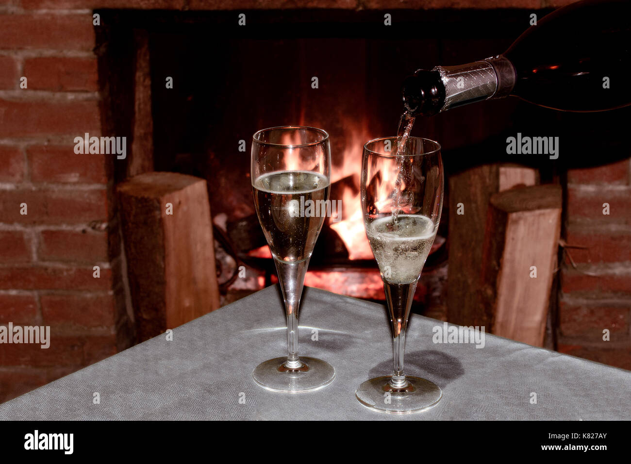 Zwei Gläser Champagner vor dem brennenden Kamin einen romantischen Abend mit Schatz zu feiern. Stockfoto