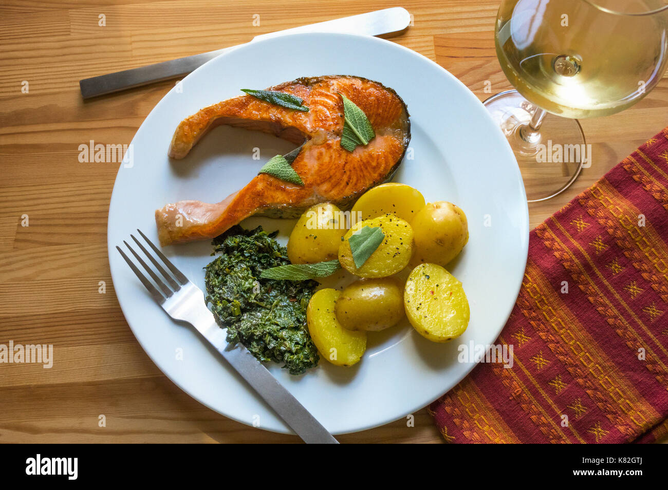 Gegrilltes Lachssteak, mit Spinat und Kartoffeln und einem Glas Weißwein Stockfoto