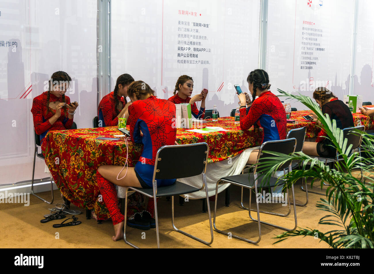 Mädchen in Spiderman Outfits, spielen mit Smartphones zu einem kulturellen chinesischen Messe in Shenzhen, Guangdong, China Stockfoto