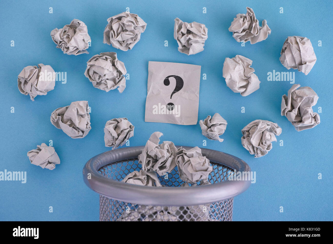 Grau zerknittertes Papier Kugeln und Fragezeichen Rollen aus einem Mülleimer. Close Up. Stockfoto