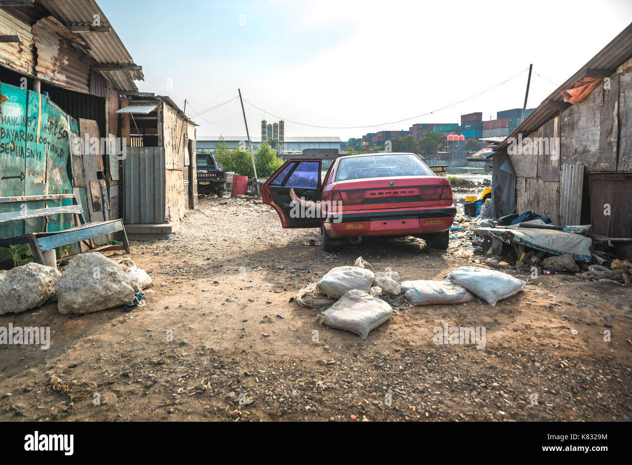 Ein Mann, der in einem beschädigten Auto schläft, parkte in der Küstengegend ganz in der Nähe von Port of Tanjung EMAS, Semarang, Indonesien. Stockfoto