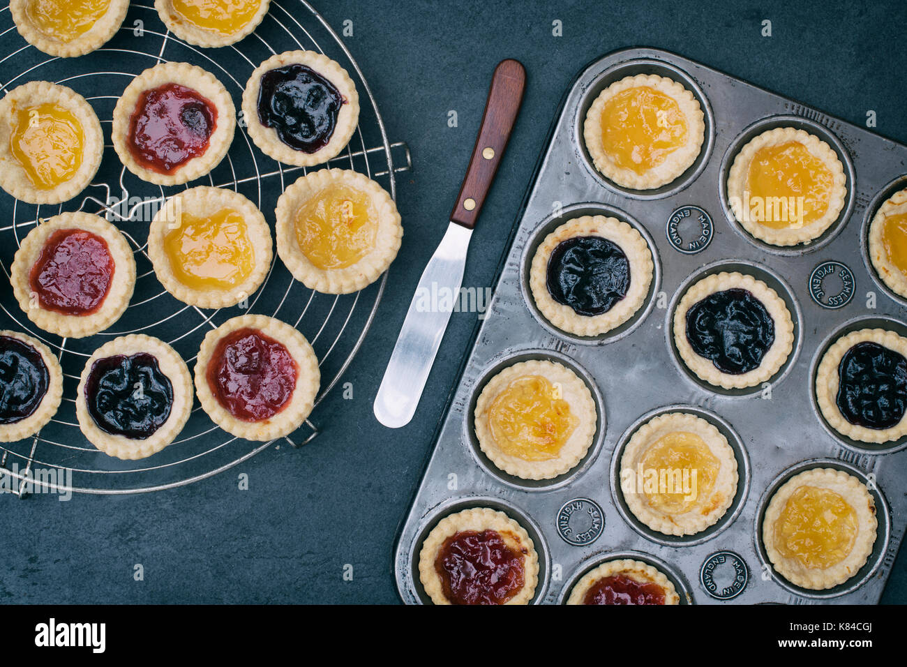 Zubereitet hausgemachte Marmeladentörtchen in einem Backblech und auf einem Vintage kreisförmigen Gitter Stockfoto