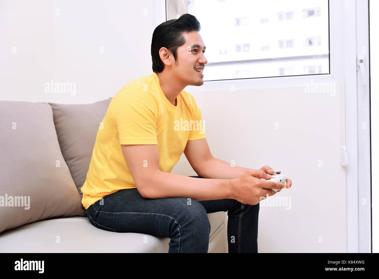 Gerne asiatische Mann mit Gamepad und Videospiele auf der Couch Stockfoto