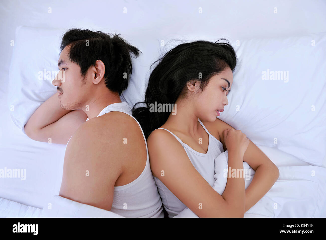 Asiatische paar Probleme mit Liegen nebeneinander im Bett, die in entgegengesetzte Richtungen im Bett umgekippt Stockfoto