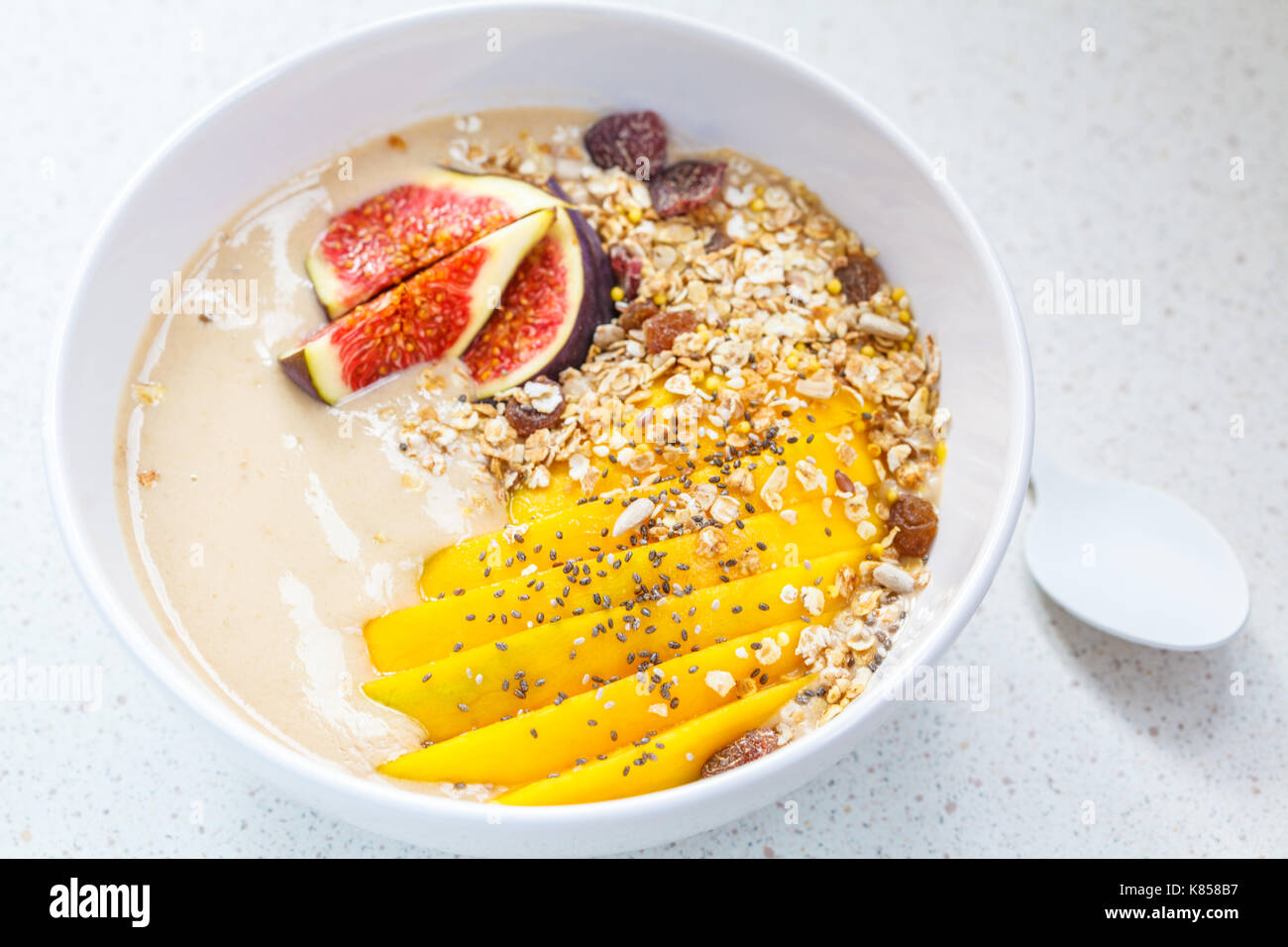 Schokolade (carob) Smoothie Schüssel Müsli, Mango, Feigen, blau konkreten Hintergrund, vegan gesundes Frühstück Konzept. Stockfoto