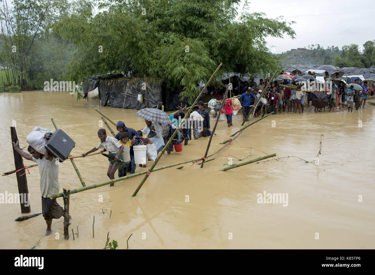 September 17, 2017 - septembar 17, 2017, Cox's Bazar, Bangladesch - Rohingya-flüchtlinge Mann zu Fuß auf einem Bambus Brücke über einen kleinen Kanal zu überqueren, wie sie von ihren temporären Lager durch den Regen zu ruinieren, die meisten Ihrer behelfsmäßigen Zelten, Kutupalong Ukhiya, Cox's Bazar bewegen. Laut UNHCR mehr als 400 tausend Rohingya-flüchtlinge Myanmar haben von Gewalt flohen in den letzten Wochen, die meisten versuchen, die Grenze zu überqueren und Bangladesch zu erreichen. Internationale Organisationen haben Nachmeldungen von Menschenrechtsverletzungen und Exekutionen angeblich durchgeführt von der myanmarischen Armee. (Bild: © K M Stockfoto