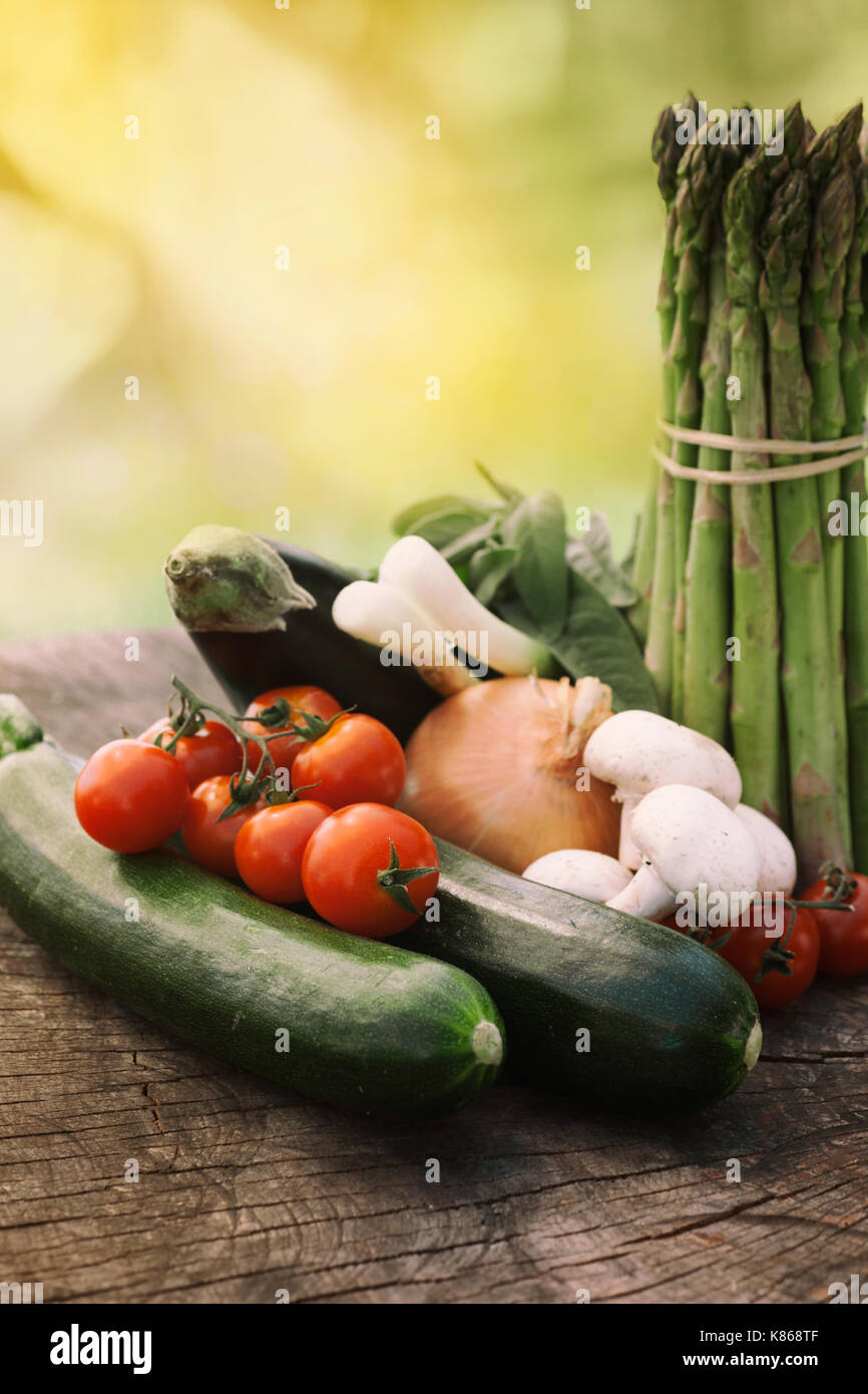 Gesunde frische Gemüse Zutaten zum Kochen in rustikaler Umgebung: Spargel, Zucchini, Pilze, Kräuter, Tomaten und Auberginen Stockfoto