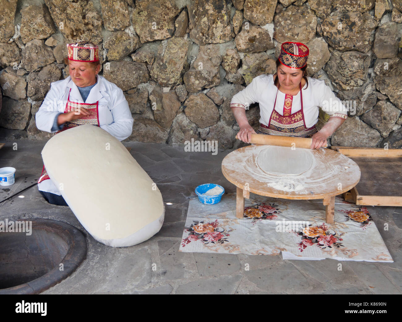 Zwei Frauen in traditionellen armenischen Kleidung Backen der leckeren Thin Out Lavash Brot in unterirdischen Backofen gerollt, Restaurant im Garni, Armenien Stockfoto