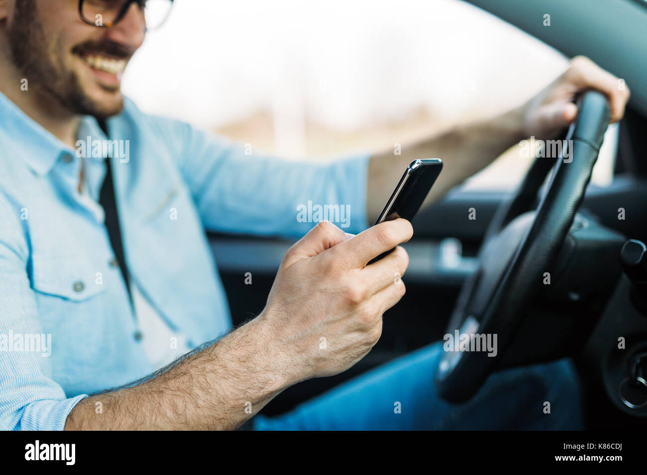 Unternehmer ignorieren Sicherheit und SMS auf Handy während der Fahrt Stockfoto