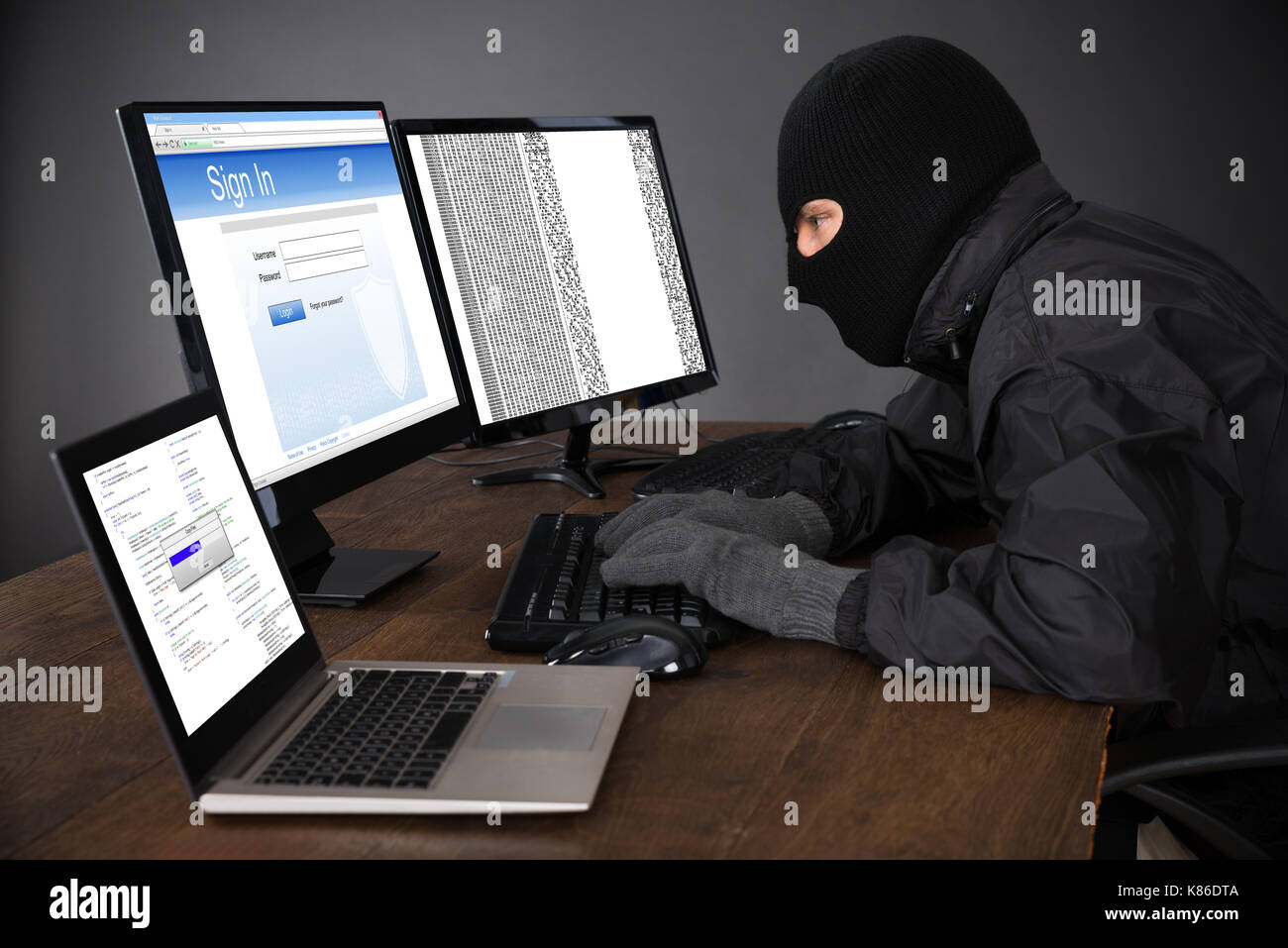 Hacker tragen Balaclava Hacking Computer am Schreibtisch Stockfoto