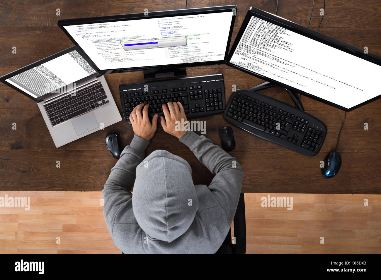Hohe Betrachtungswinkel der Hacker stehlen Informationen von Computern am Schreibtisch Stockfoto