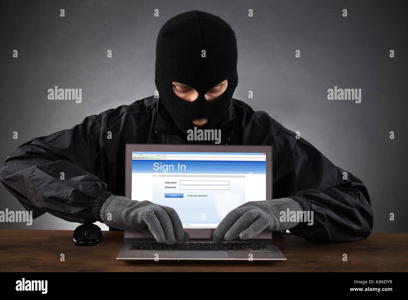 Hacker Hacking Account von Social Networking Website auf Laptop am Schreibtisch Stockfoto