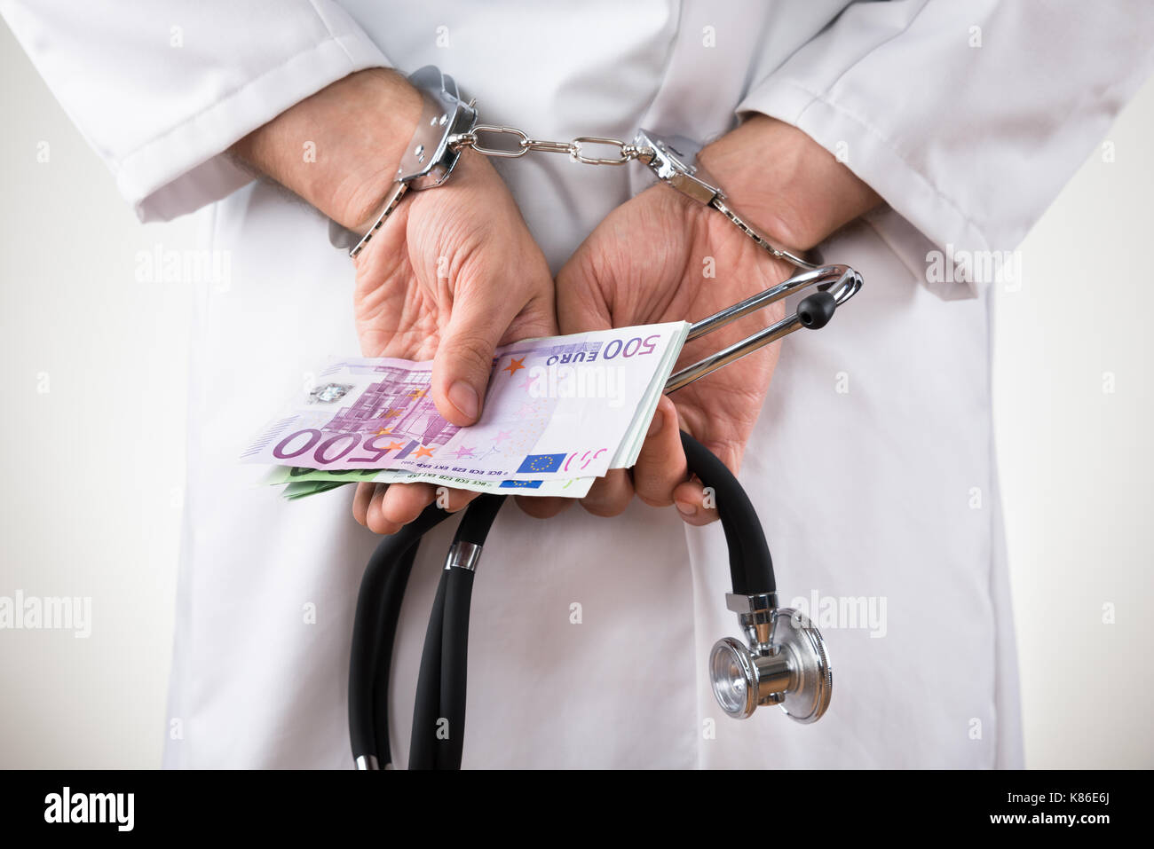 Nahaufnahme eines Doktors Hand mit Euro Banknoten und Handschellen Stockfoto