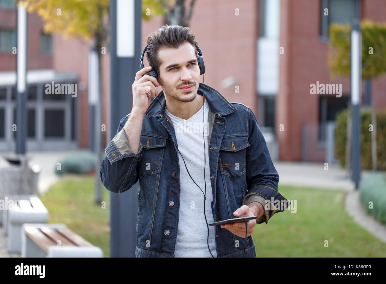 Junge legerer Mann hören Musik von Tablet outdoor im Herbst Stockfoto