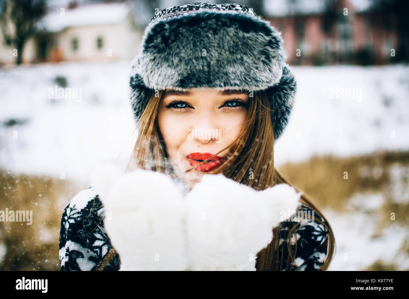Schöne junge Frau trägt warme Mütze und Handschuh Schneeverwehungen im Winter Natur Stockfoto