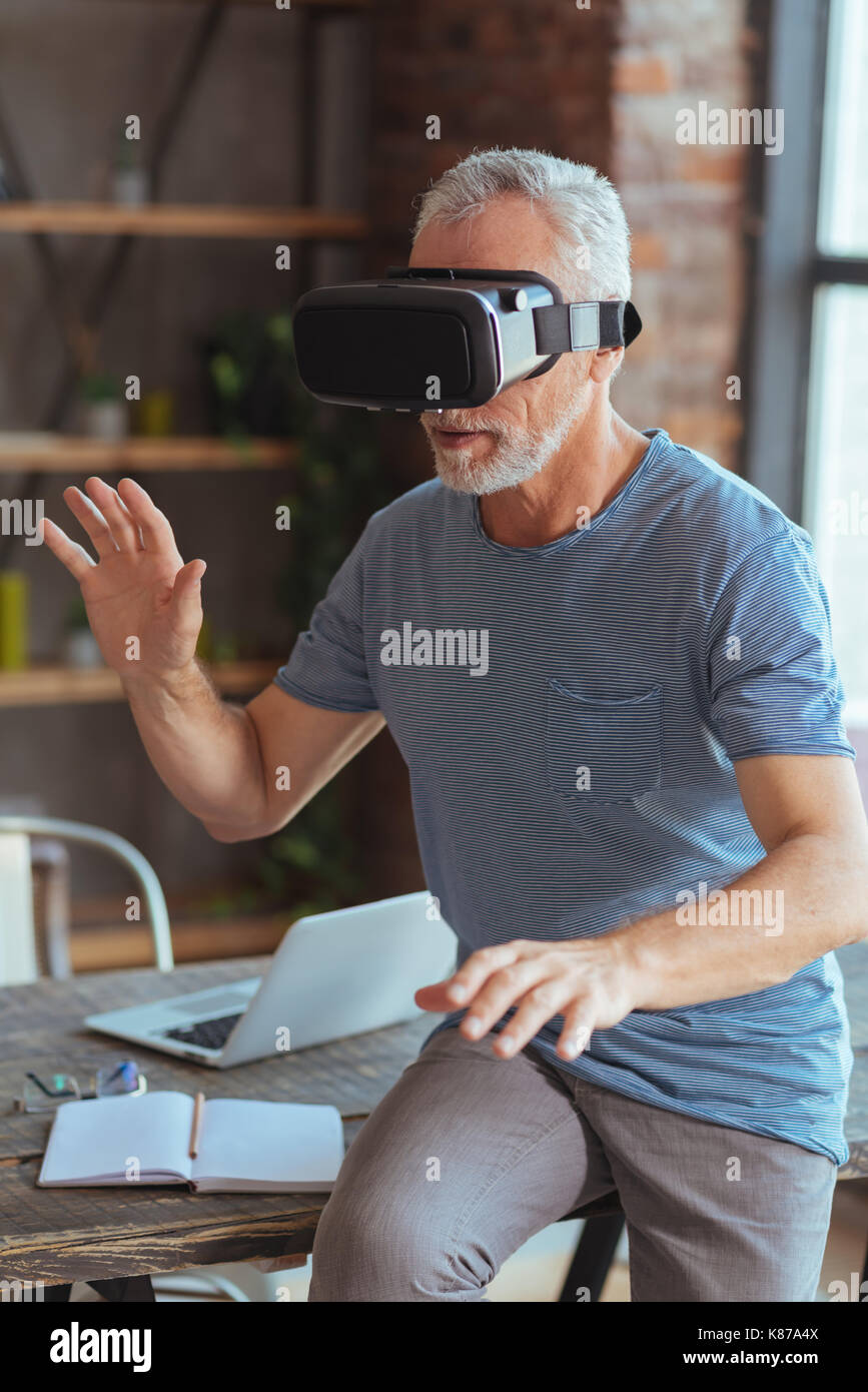 Neugierig alter Mann testen VR-Brille zu Hause Stockfoto