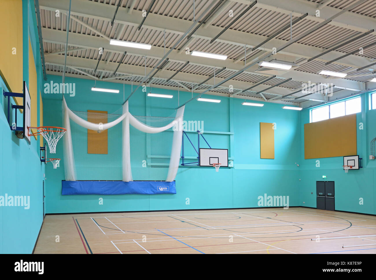 Sporthalle in einer neuen britischen Secondary School. Zeigt basket ball Ziele und Cricket Netze Stockfoto