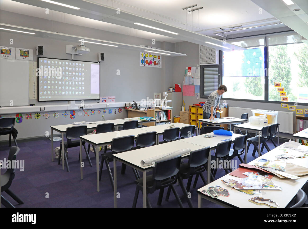 Ein Lehrer arbeiten alleine in einem modernen Unterricht in einem neuen London secondary school. Traditionelle Layout mit Schreibtischen mit Blick auf einen großen Bildschirm. Stockfoto