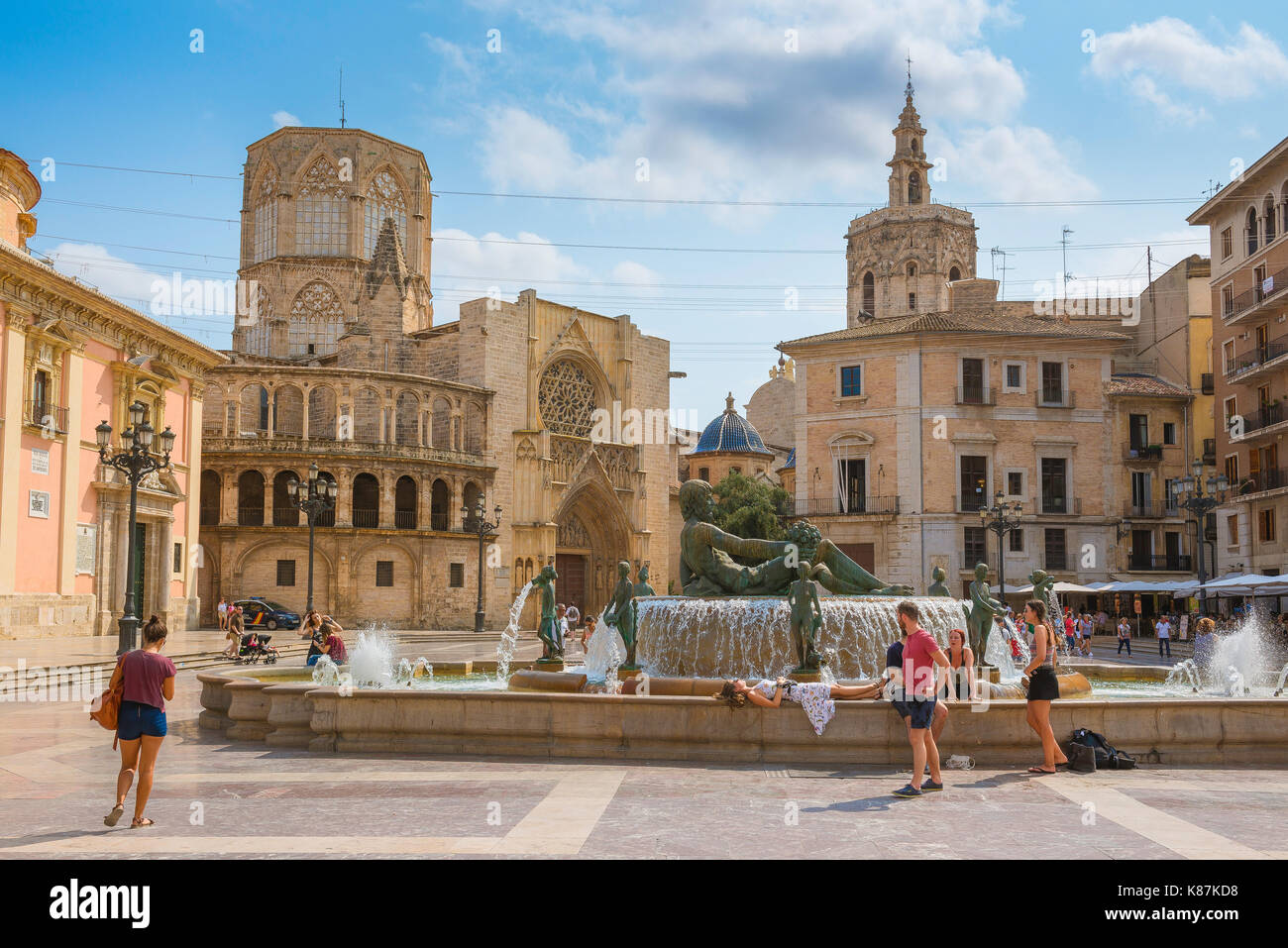 Valencia, Blick auf Touristen, die sich um den Brunnen auf der Plaza de la Virgen mit der Kathedrale und ihren zwei Türmen im Hintergrund entspannen, Valencia, Spanien Stockfoto
