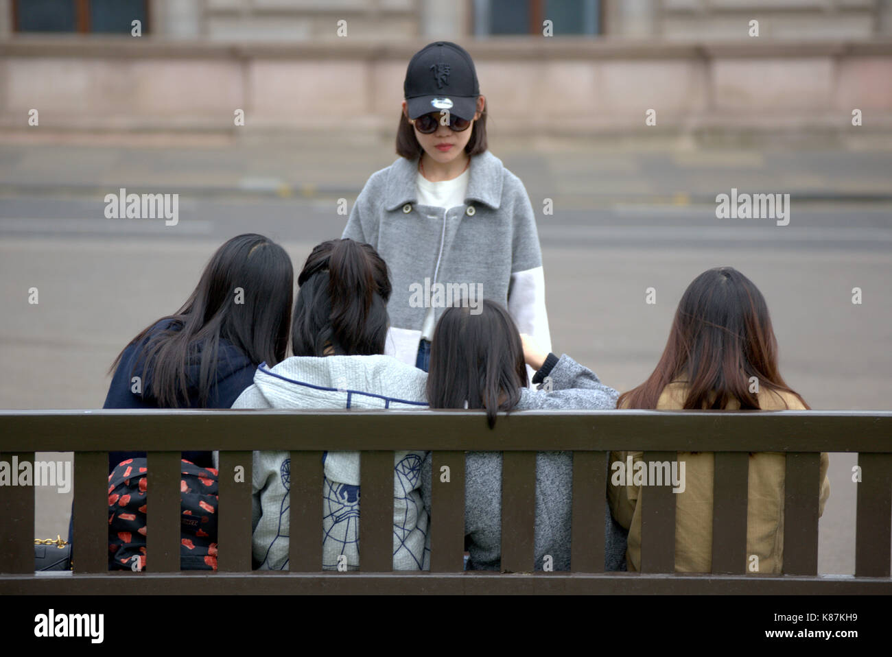 Chinesische Mädchen Spaß auf einer Bank sitzen George Square Glasgow Stockfoto