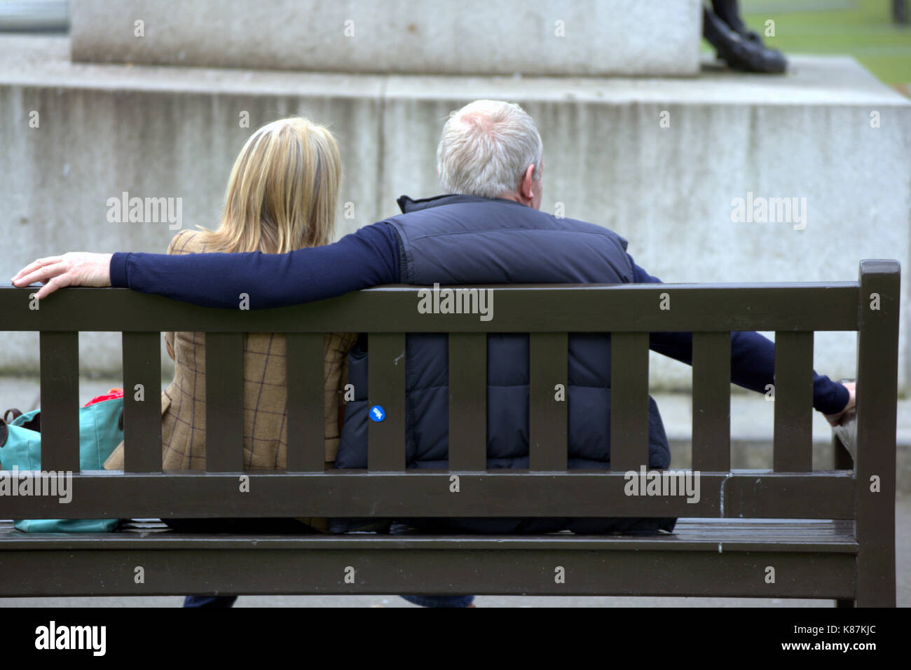 Ältere Paar mittleren Alters Arm in Arm auf einer Bank sitzen George Square Glasgow Stockfoto