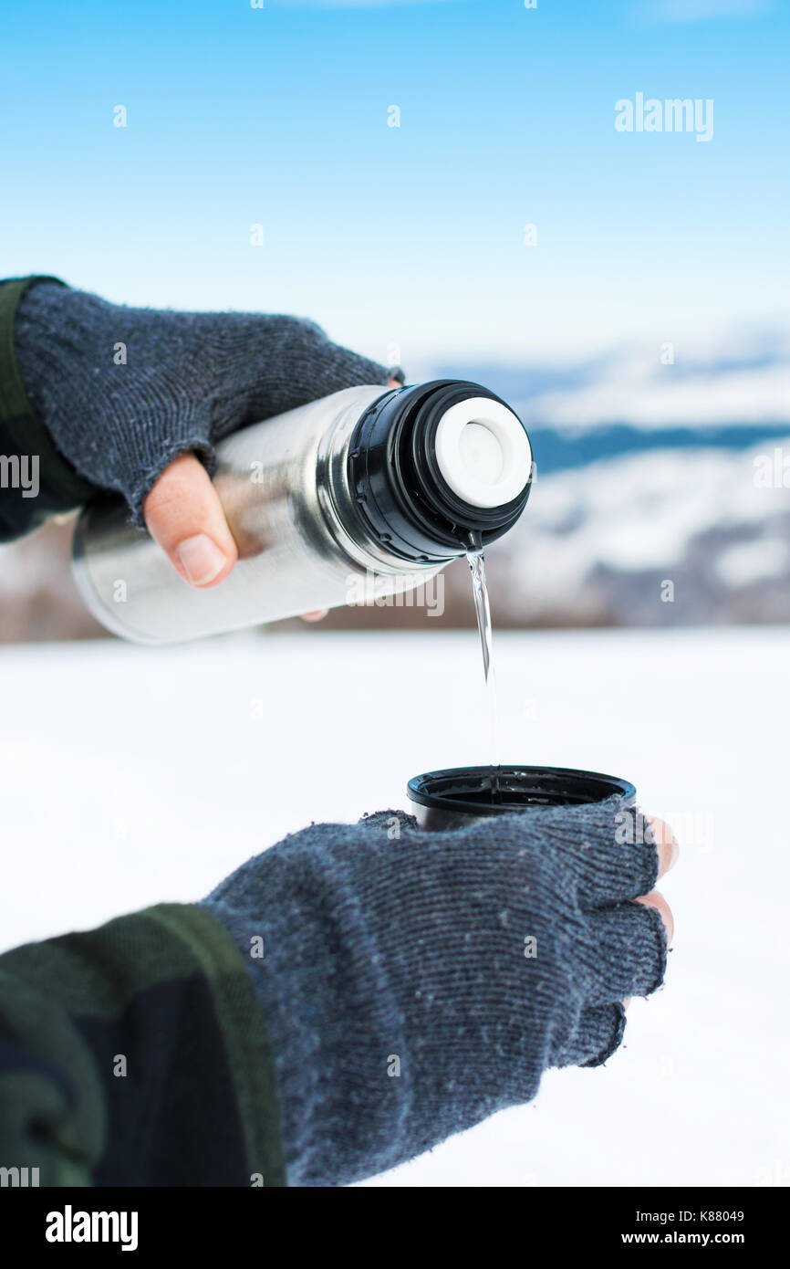 Mann mit Thermosflasche auf den verschneiten Berg Stockfoto