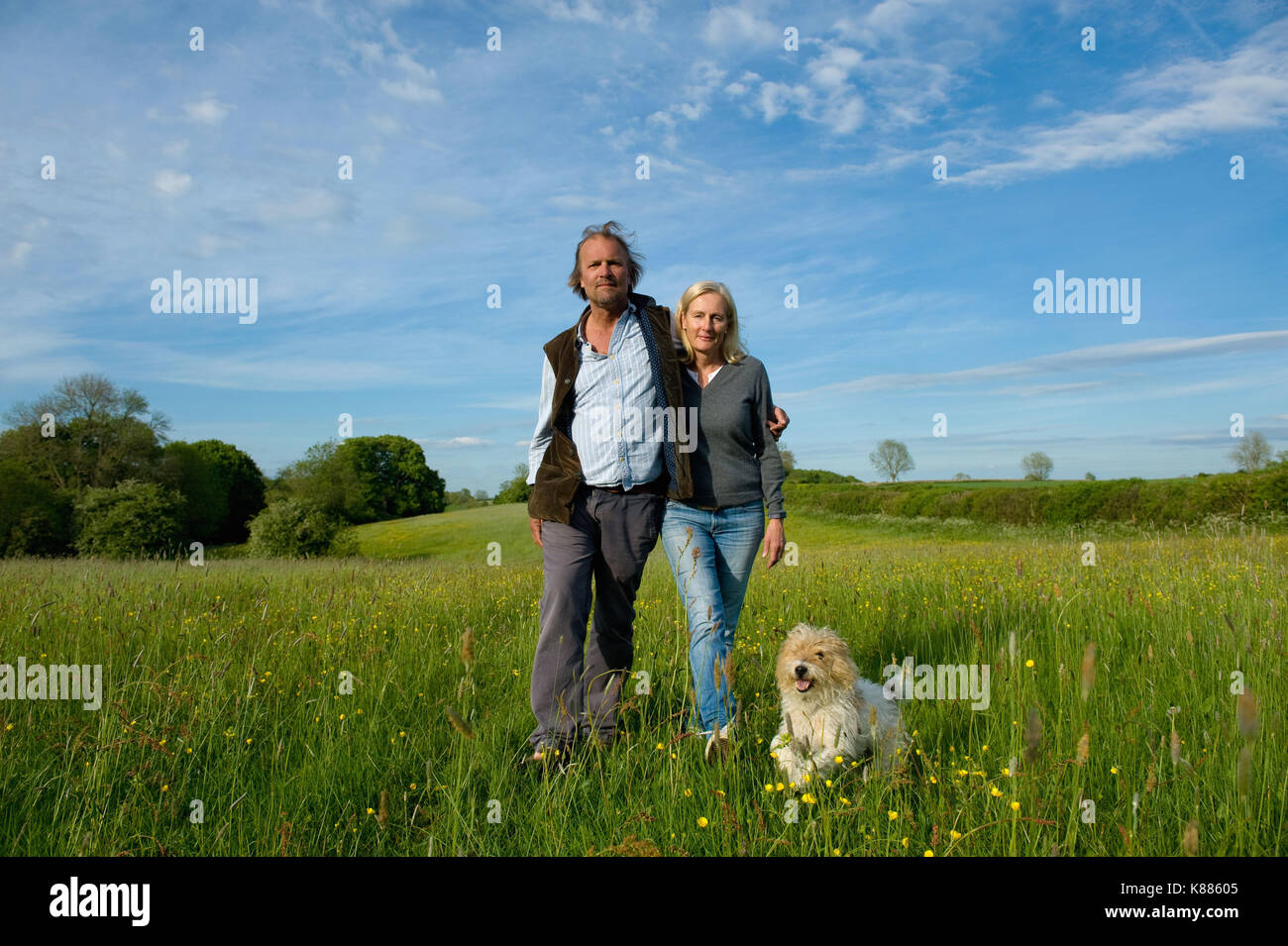 Der Mann und die Frau zu Fuß Arm in Arm über eine Wiese, kleinen Hund läuft neben Ihnen. Stockfoto