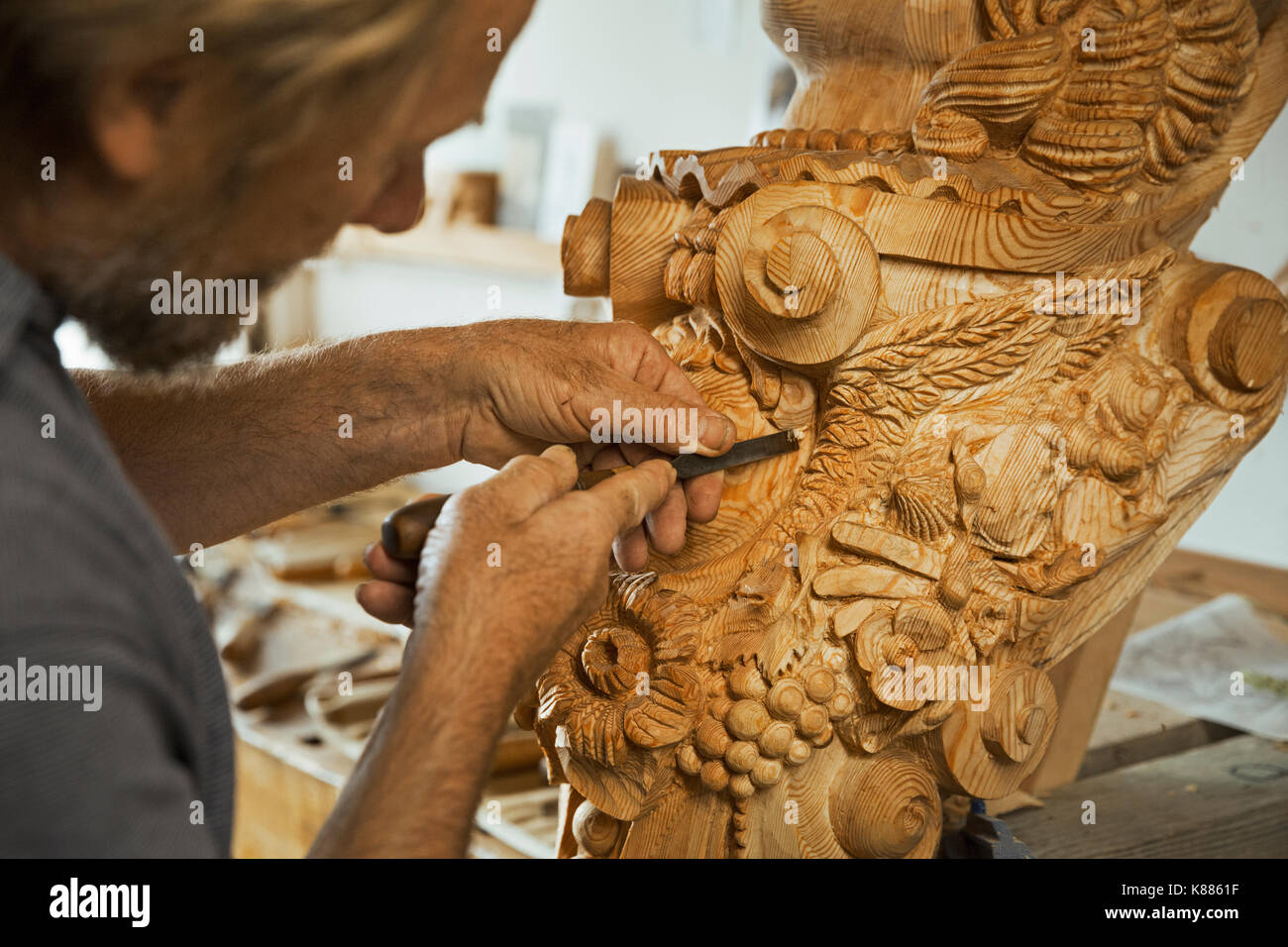 Nahaufnahme von einem Handwerker arbeiten mit einer Hand, mit einem kleinen Holzbearbeitung Meißel auf die Hölzerne dekorative Eigenschaften von einem Schiff Aushängeschild in einem funktioniert Stockfoto