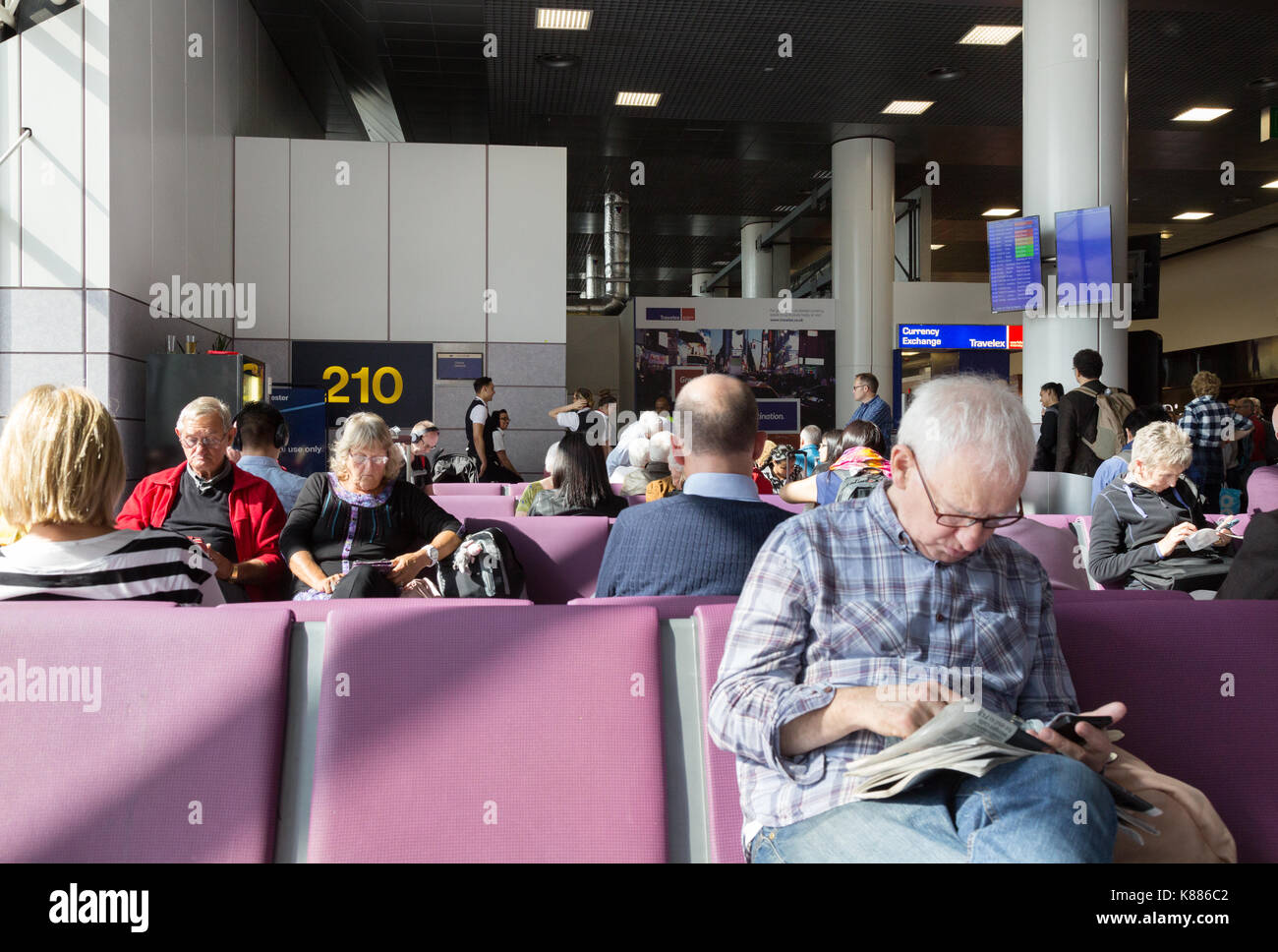 Fluggäste an der Pforte sitzen, Terminal 2, Flughafen Manchester, Großbritannien Stockfoto