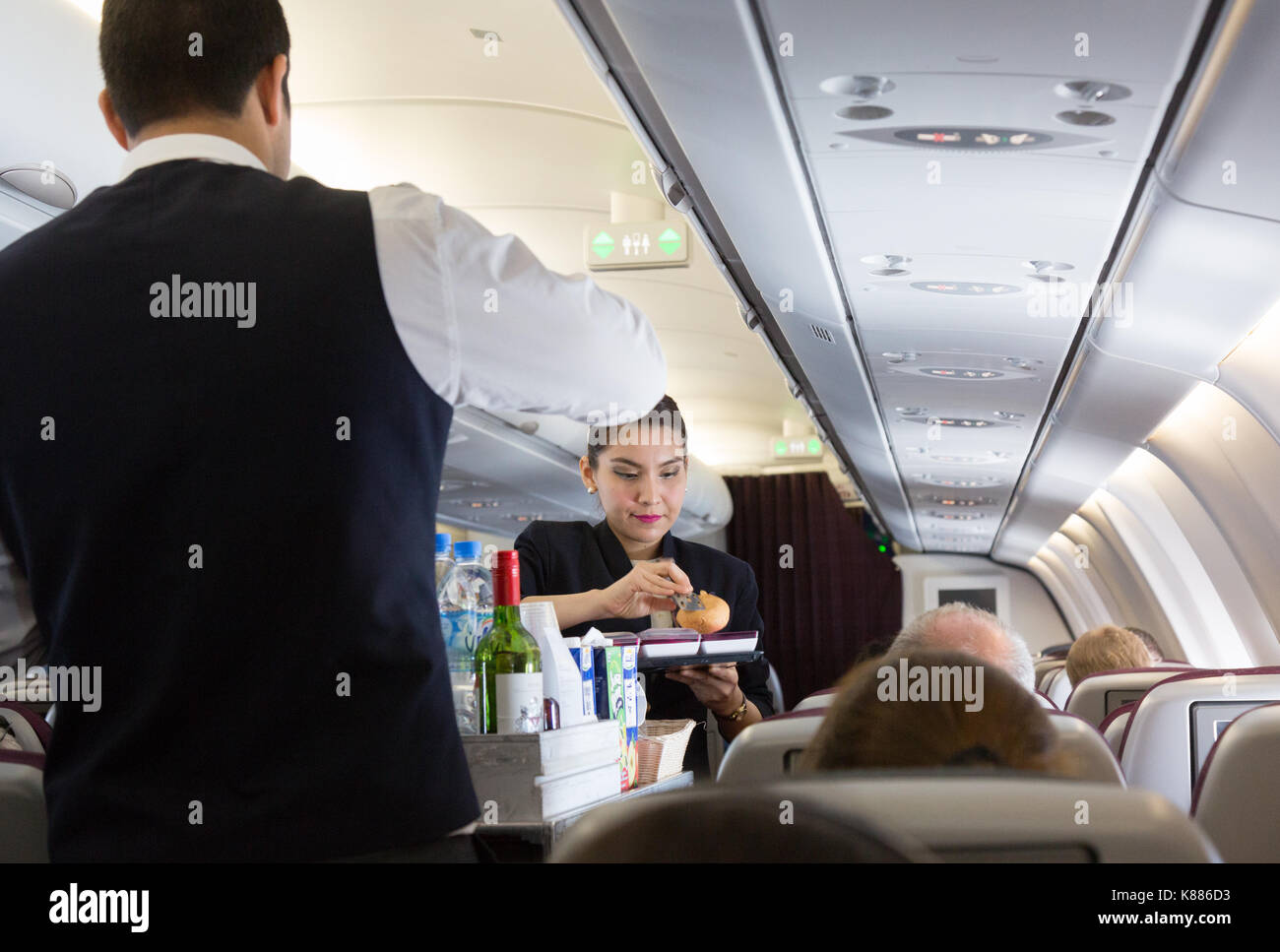 Qatar Airways - Cabin Crew, die an Bord; - die Stewardess das Essen auf einem A330-Flug Malediven zu Doha Stockfoto