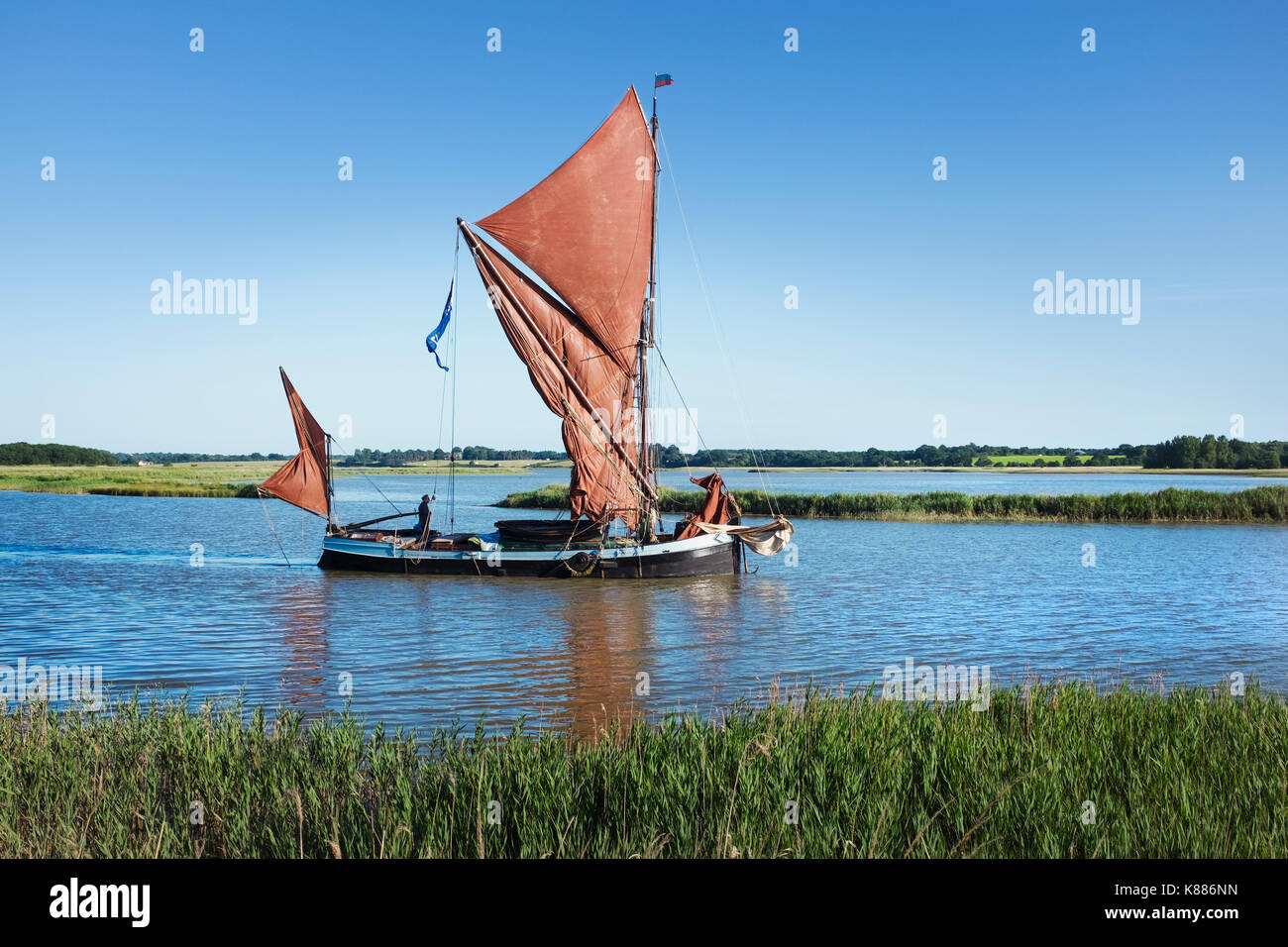 Traditionelle Segelboot mit rotem Segel und einem gaffelrigg, Segeln mitten auf dem Wasser auf ein Rohr oder Flussmündung. Stockfoto