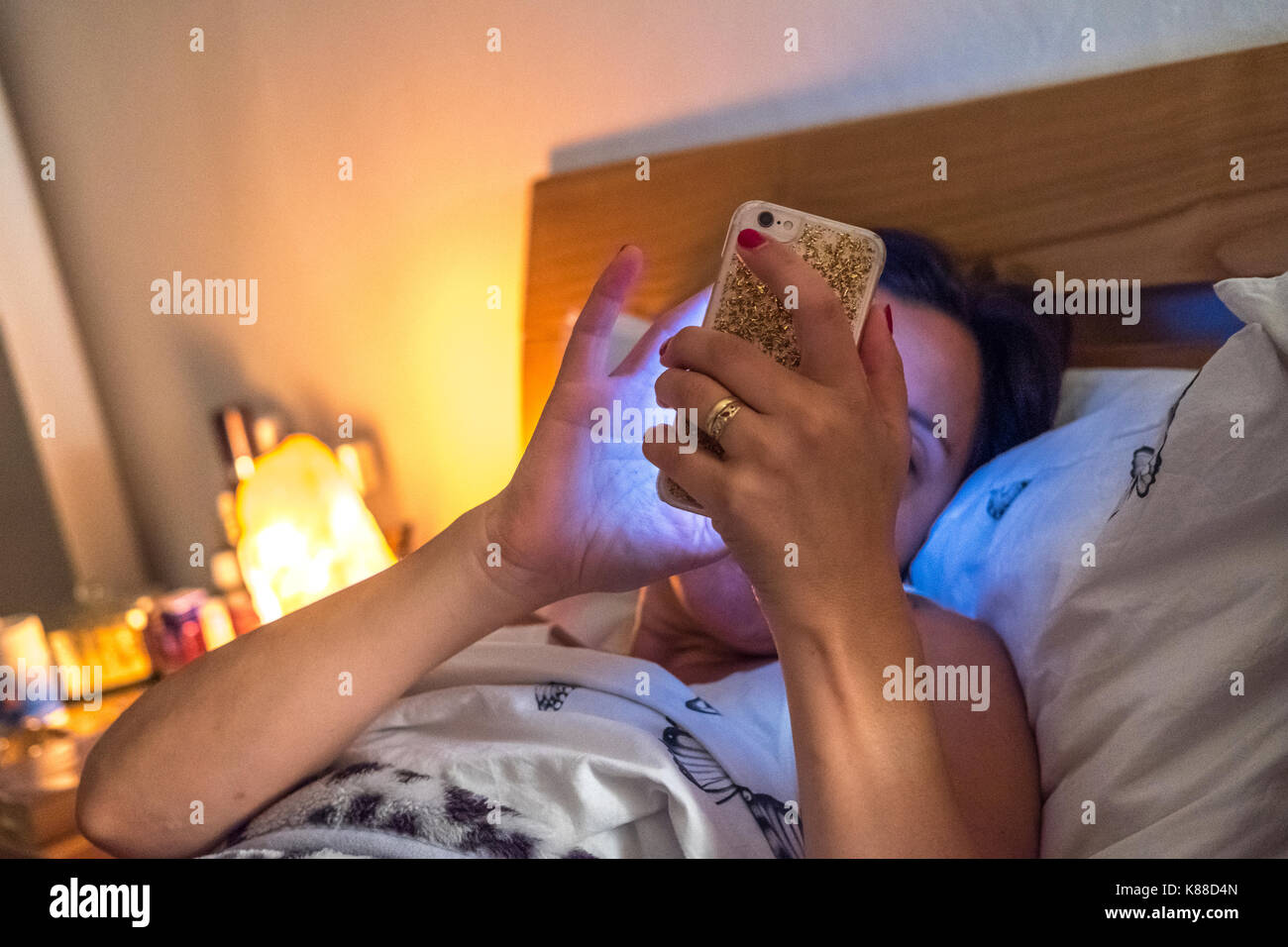 EWoman auf Ihrem smart phone im Bett Stockfoto