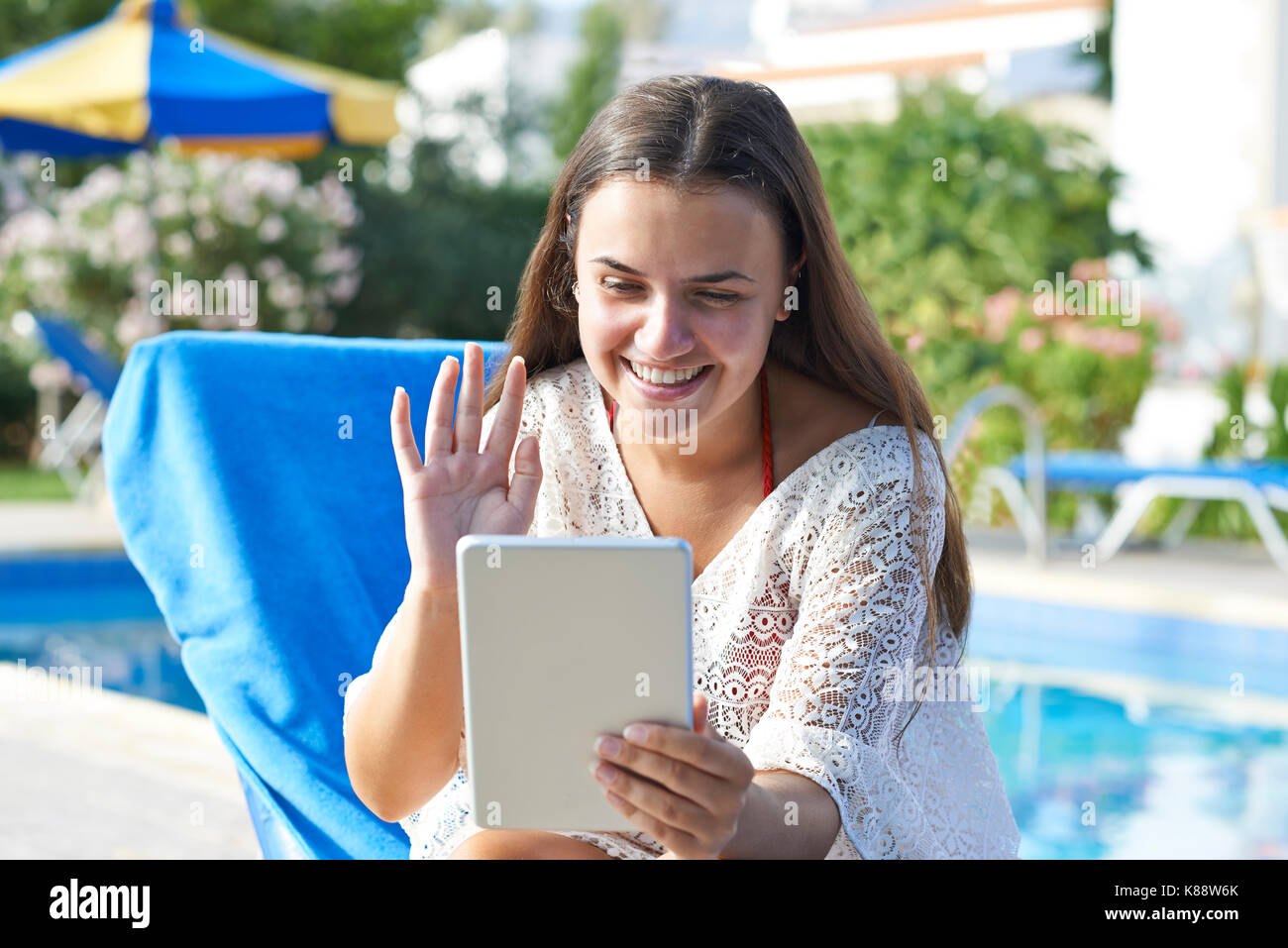 Junges Mädchen mit digitalen Tablet beim Entspannen durch Swimming-pool im Urlaub Stockfoto