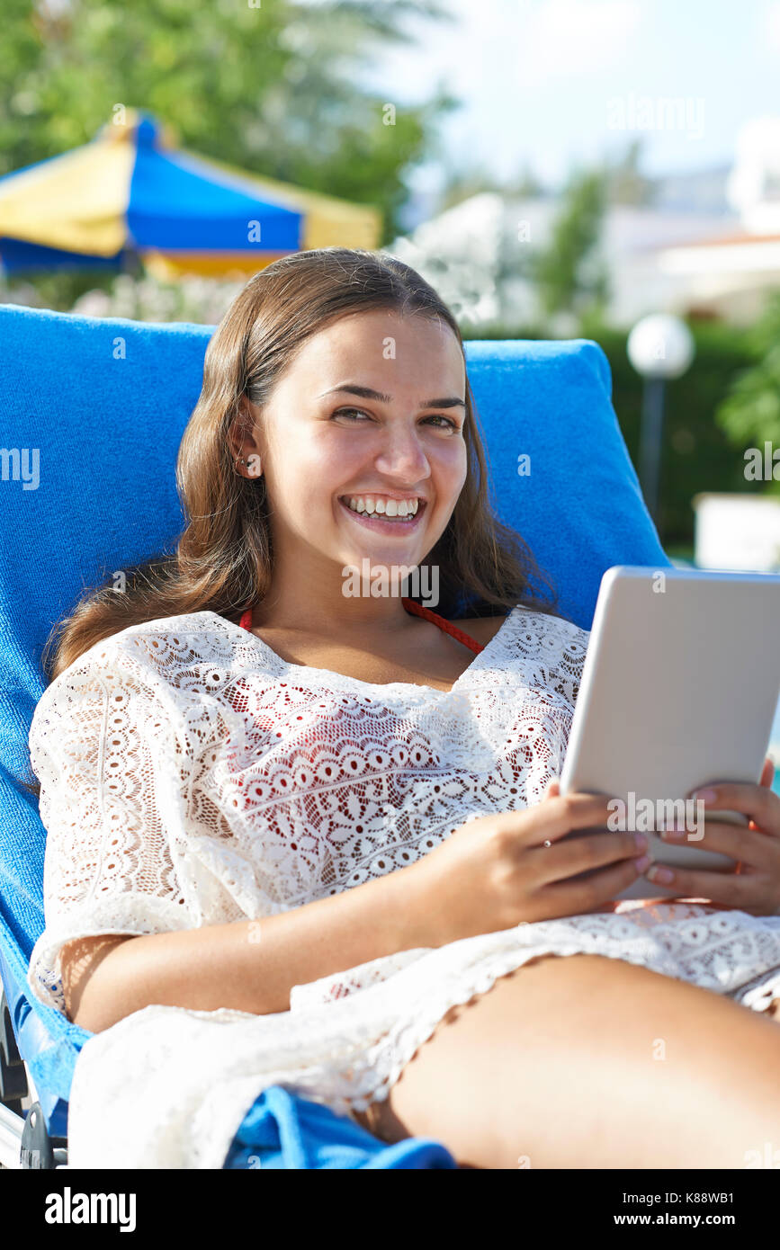 Junges Mädchen mit digitalen Tablet beim Entspannen durch Swimming-pool im Urlaub Stockfoto