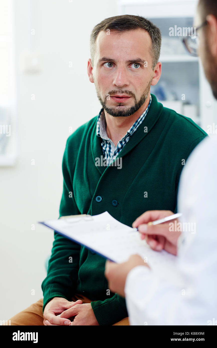 Junger Mann hören Beratung in der Arztpraxis für den Arzt Stockfoto
