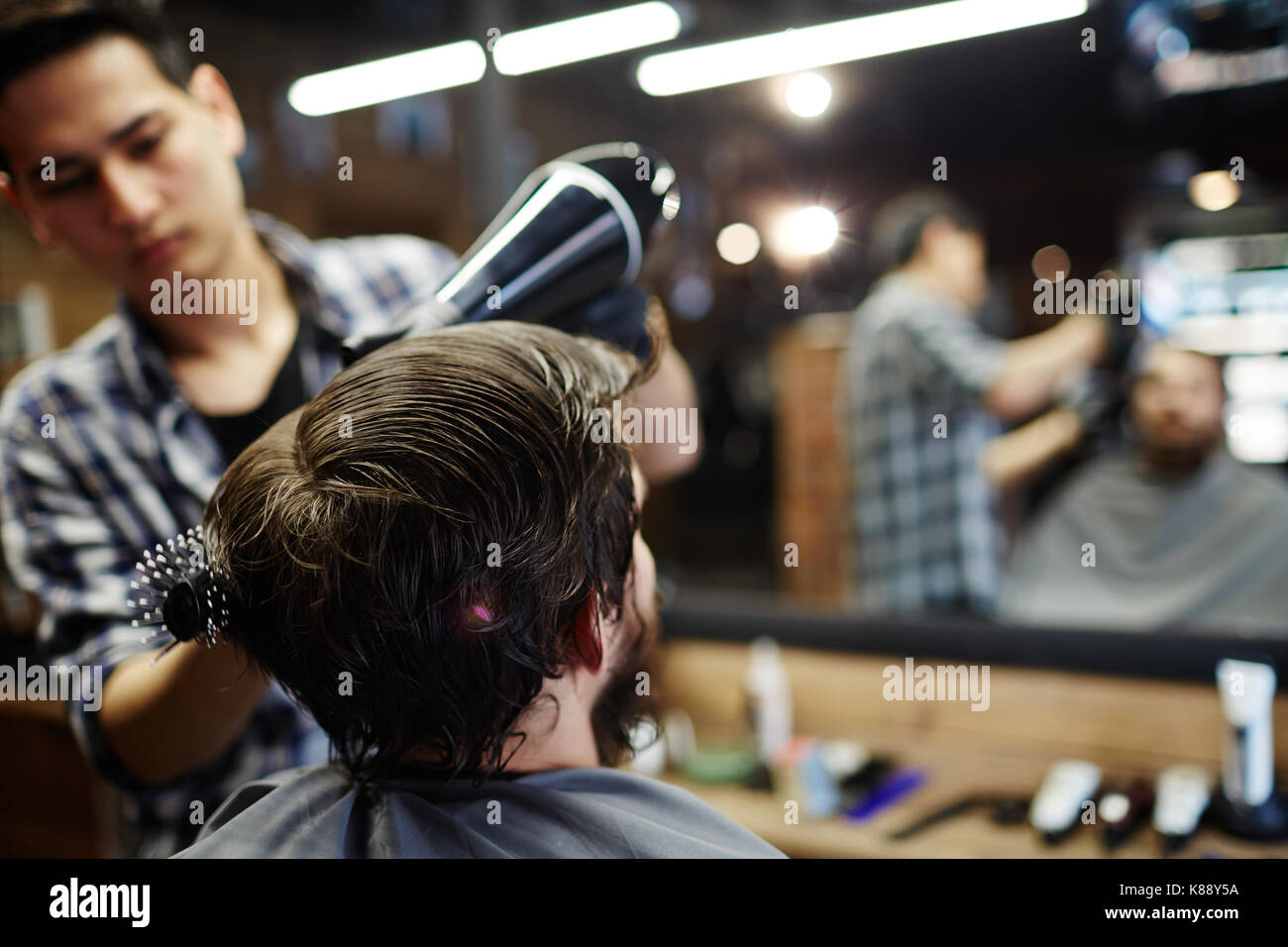 Friseur Client seine Haar getrocknet mit Fön und mit Haarbürste styled Stockfoto