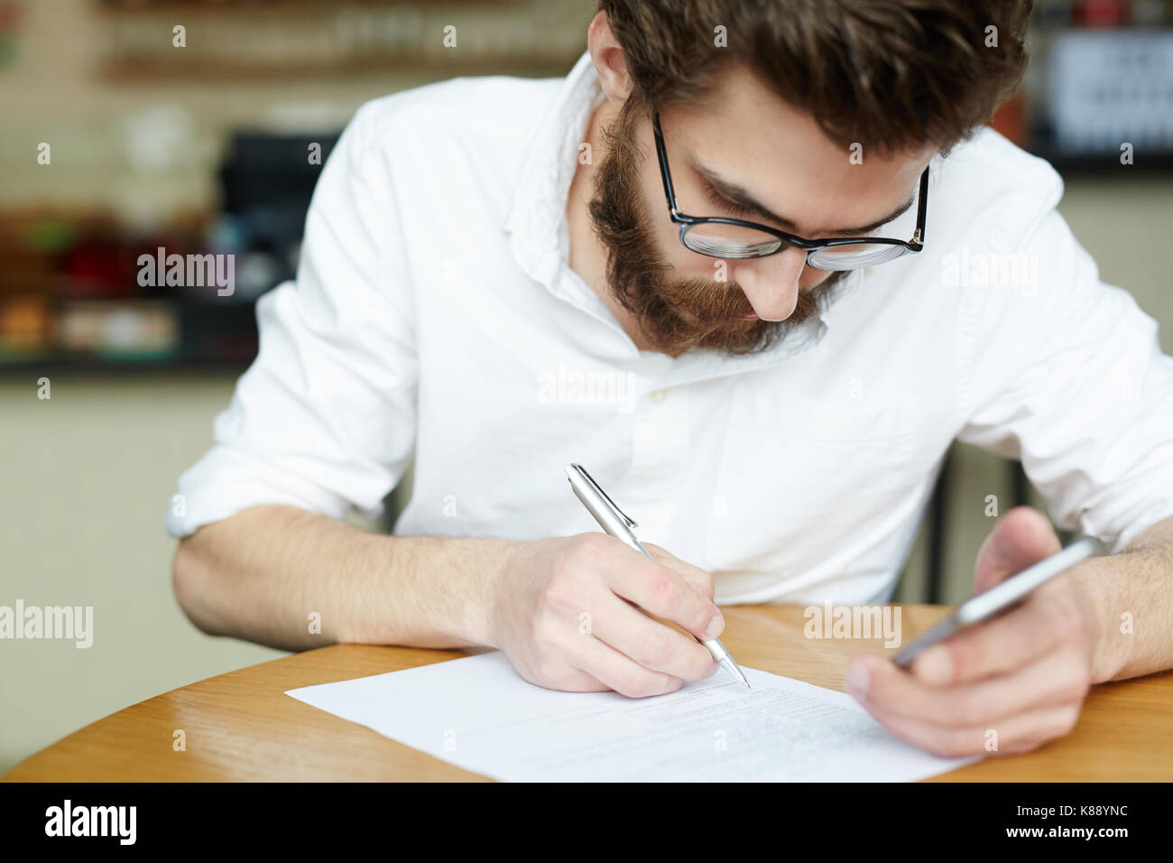 Junge Bewerber lesen Vertrag durch den Arbeitgeber gegeben, bevor sie es unterzeichnet Stockfoto