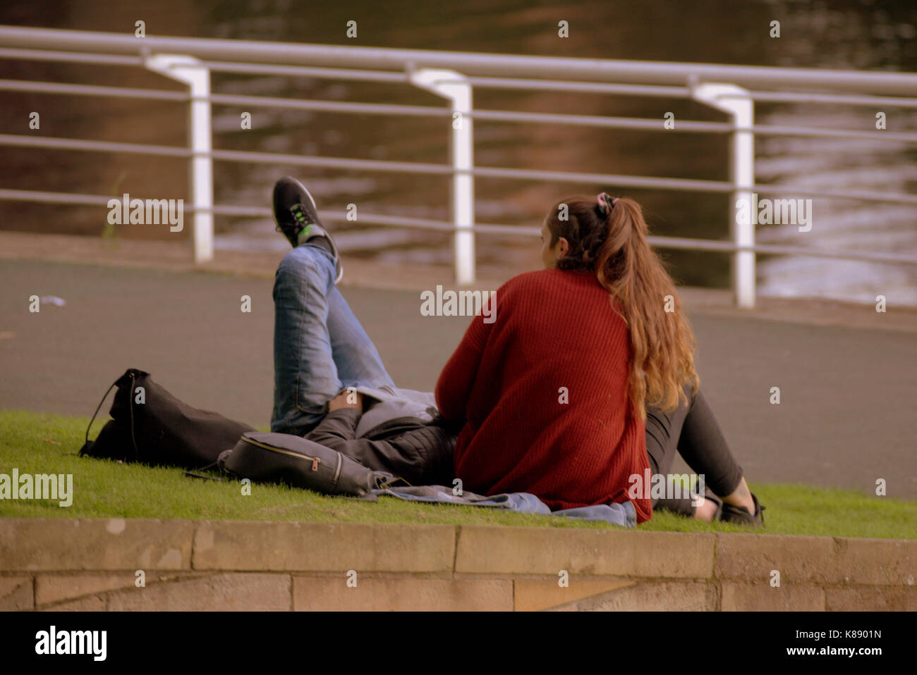 Touristische Paare sitzen auf dem Gras am Ufer des Flusses Clyde Glasgow Schottland Stockfoto