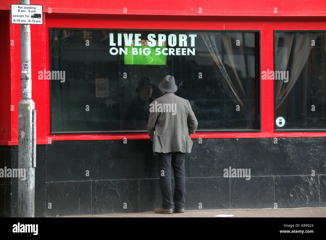 Menschen auf der Straße beobachten Live-Sport im TV kostenlos rote Pub an der Wand den ganzen Tag Menü Stockfoto