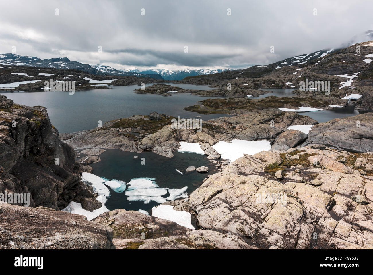 Typisch norwegische Landschaft mit schneebedeckten Bergen und Clear Lake in der Nähe der berühmten Aurlandsvegen (Bjorgavegen), Mountain Road, Aurland, Norwegen. Stockfoto