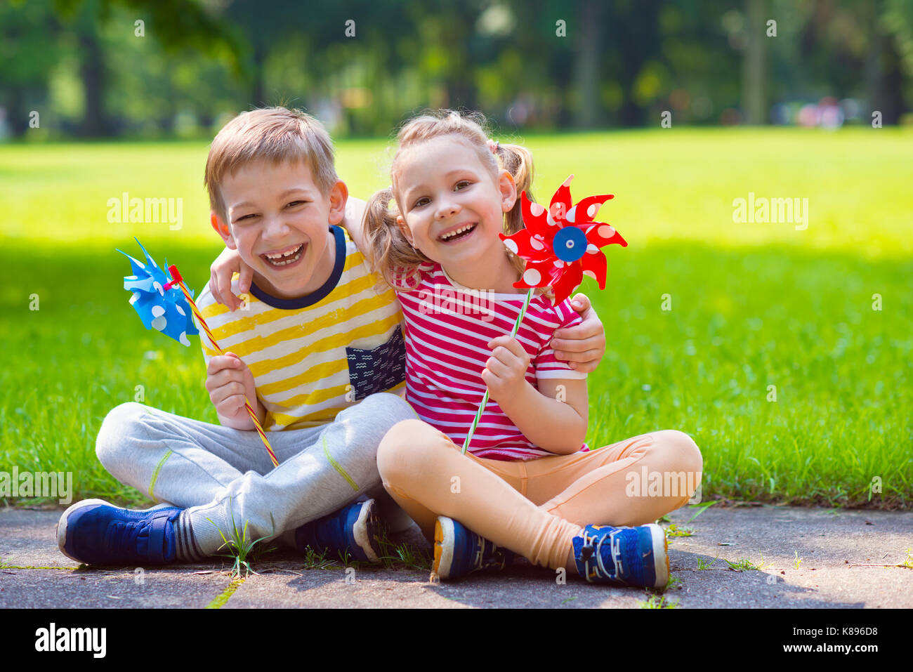 Zwei glückliche Kinder spielen im Garten mit Windmühle Stockfoto