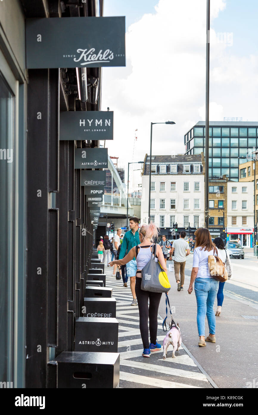Geschäfte in Shoreditch Boxpark, Menschen zu Fuß auf Bethnal Green Road, London, UK Stockfoto