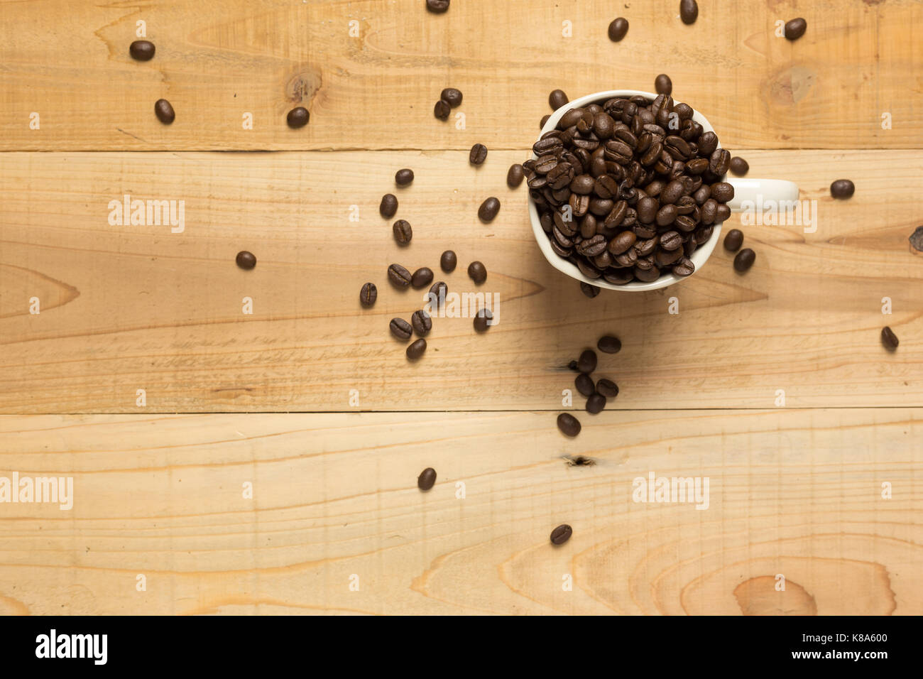 Kaffeebohnen in eine Tasse Kaffee auf hölzernen Tisch. Stockfoto