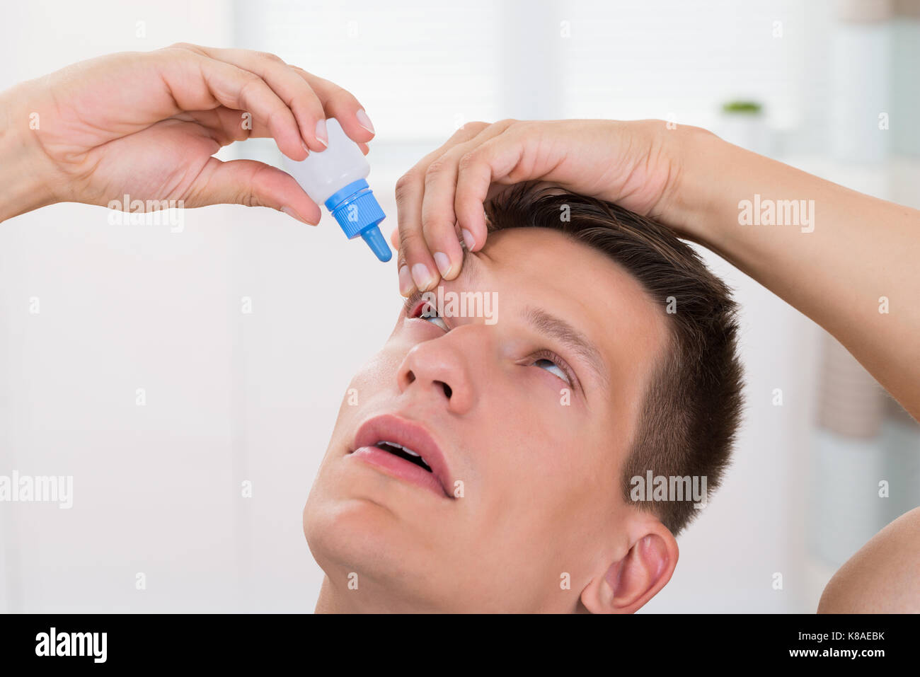 Close-up des jungen Mannes Gießen Medizin Tropfen in die Augen Stockfoto