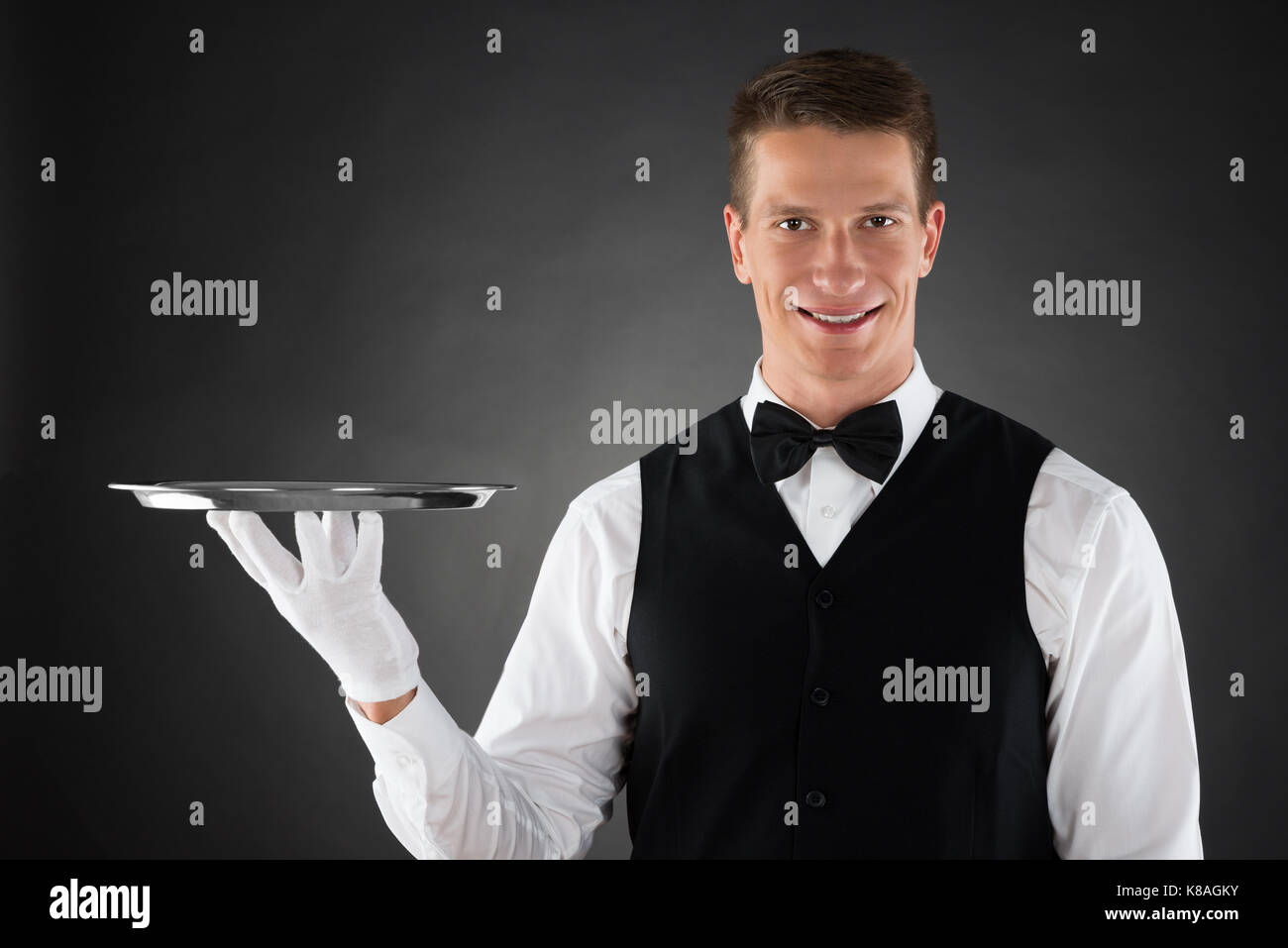 Junger Kellner Holding Silber Tablett in den Händen Stockfoto